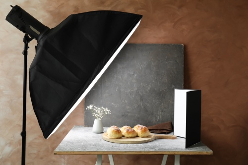 Kulisy zdjęć produktowych wypieków, z lewej softbox centralnie wypieki, z prawej akcesoria do odbijania światła