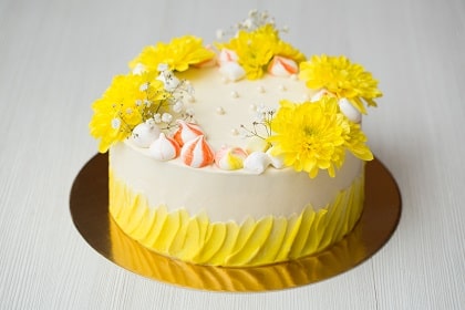 Tort na złotym podkładzie udekorowany za pomocą kwiatów